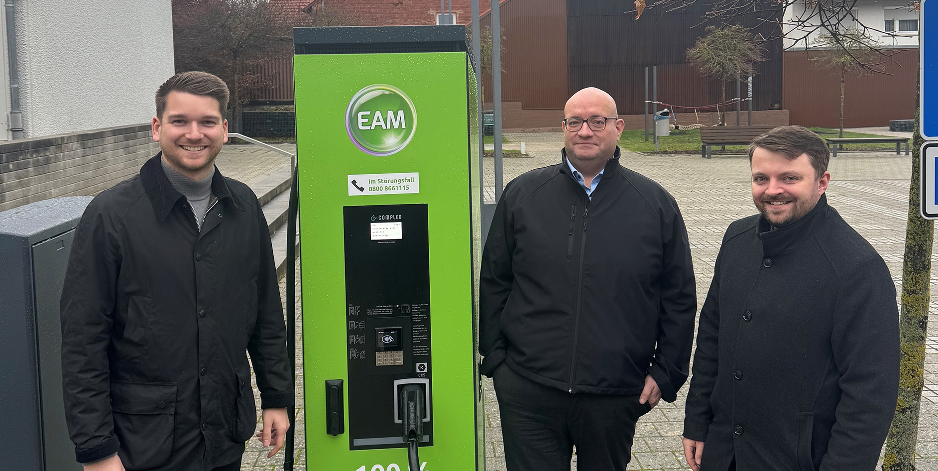Freuen sich über die neue Ladesäule in Friedewald (v. l. - stehen um die grüne EAM-Ladesäule verteilt und schauen in die Kamera): Bürgermeister Julian Kempka, Michael Bräutigam (EAM Natur Energie / E-Mobilität) und André Jüttner (Vertreter Leiter Netzregion Borken).