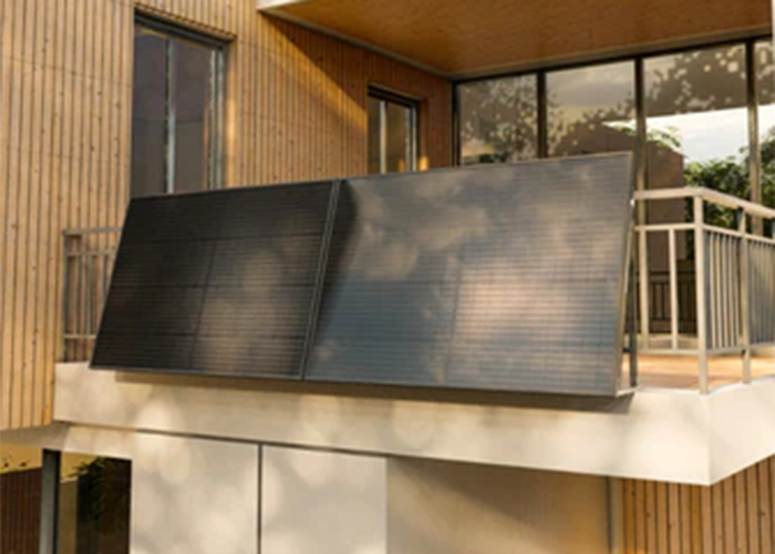 Solaranlage auf einem modernen Balkon eines Holzhauses mit großen Fenstern.