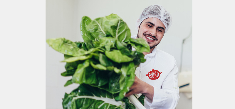 Ein Koch am Lachen mit einem Salat in der Hand.