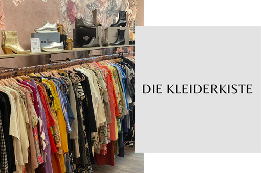Kleiderständer mit bunten Bekleidungsstücken in einem Modegeschäft, im Hintergrund Schuhregal und dekorative Wand.
