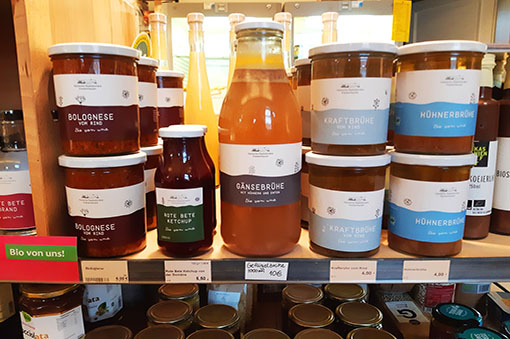 Regal mit verschiedenen Glasbehältern, darunter Gänsebrühe, Bolognese und Ketchup. Bio-Produkte aus dem Sortiment.