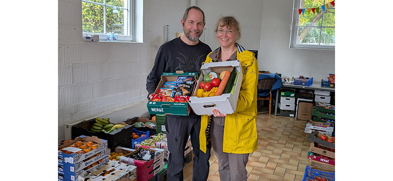Mann und Frau halten eine Box mit Obst und Gemüse in die Kamera