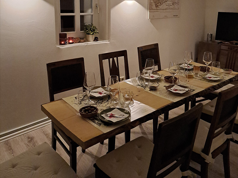 Ein festlich gedeckter Tisch mit Gläsern, Geschirr und Kerzen in einem gemütlichen Raum.