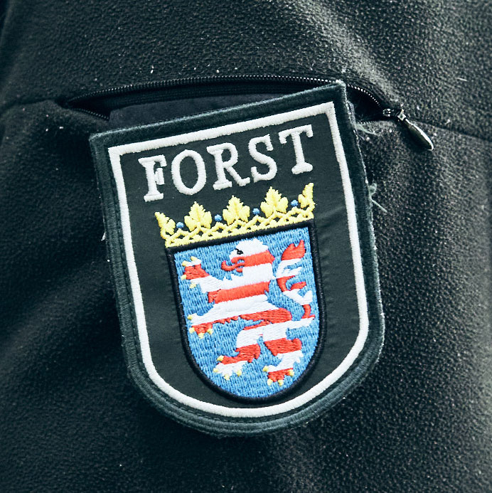 Emblem des Forsts mit Wappen und dem Schriftzug "FORST"" auf einem schwarzen Hintergrund."