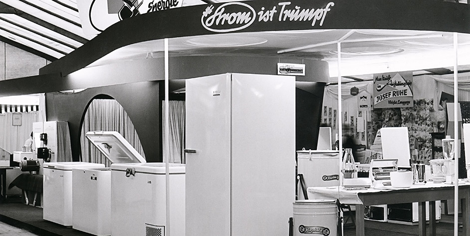 Schwarze und weiße Fotografie eines Verkaufsstands mit Kühlgeräten und einem Schild "Vom ist Triumph""."