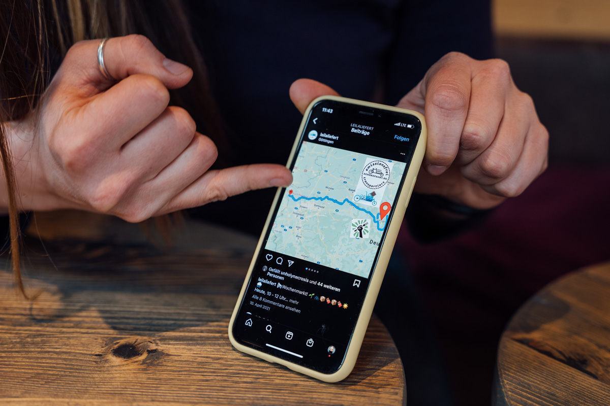 Eine Person zeigt auf eine Karte auf einem Smartphone, das eine Route zwischen zwei Punkten anzeigt.