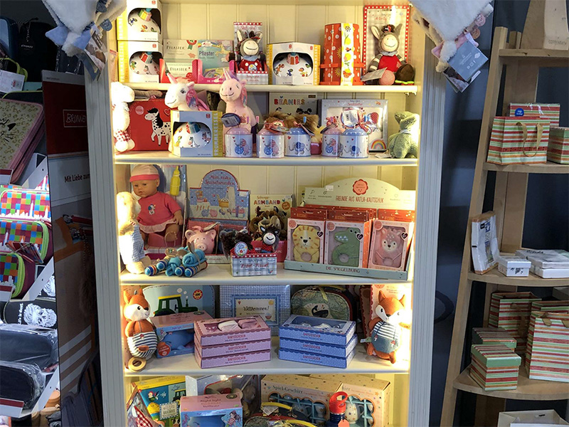 Bunte Regale mit Spielzeug, Plüschtieren, Verpackungen und Geschenkideen für Kinder.