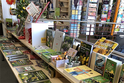 Regal mit verschiedenen Gartenbüchern und Dekoartikeln in einem Verkaufsraum.