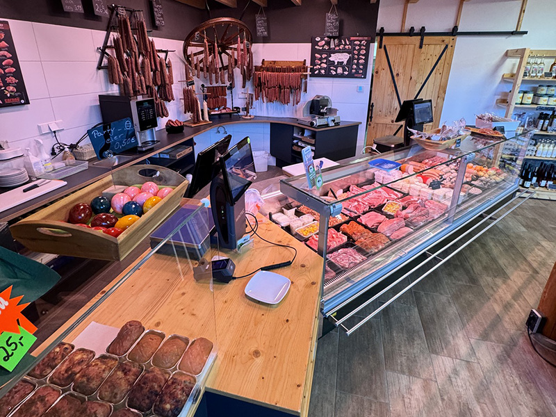 Theke eines Fleischgeschäfts mit verschiedenen Fleischsorten, Wurstwaren und bunten Dekorationen.