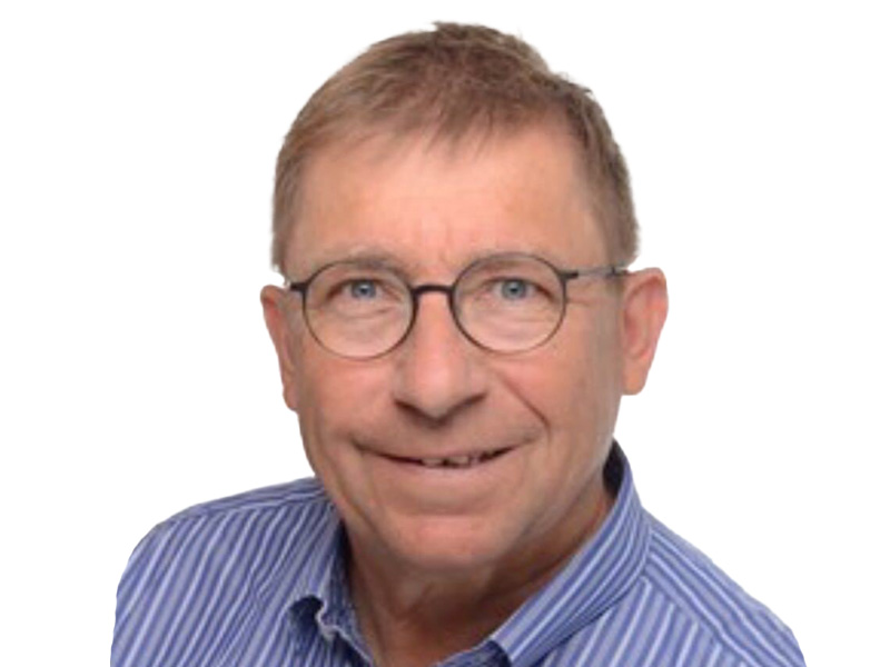 Porträt eines lächelnden Mannes mit Brille, blauer gestreifter Hemd, auf weißem Hintergrund.