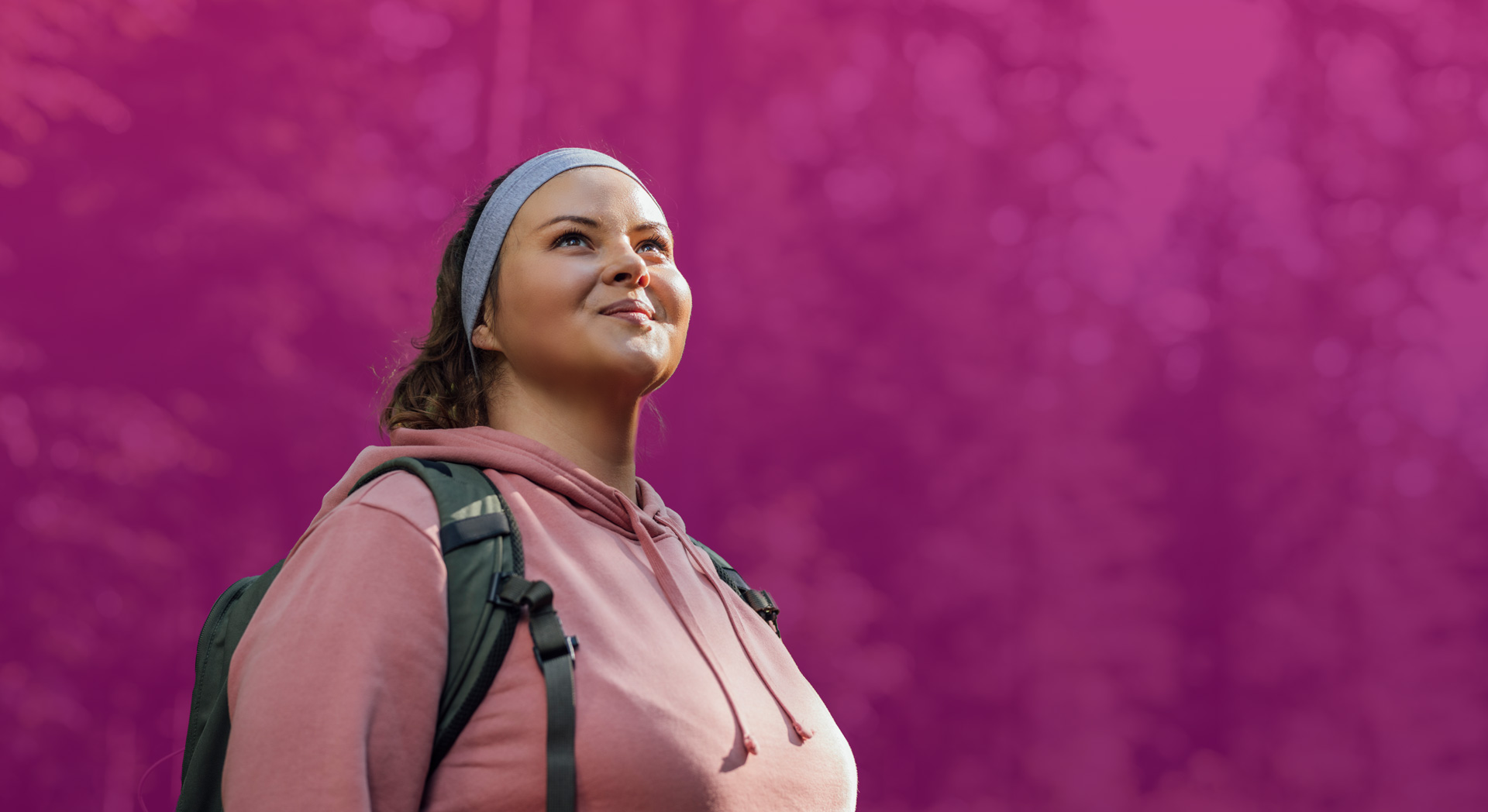 Junge Frau in lockerem Outfit mit Rucksack, schaut optimistisch in den Himmel, umgeben von einem lila verschwommenen Hintergrund.
