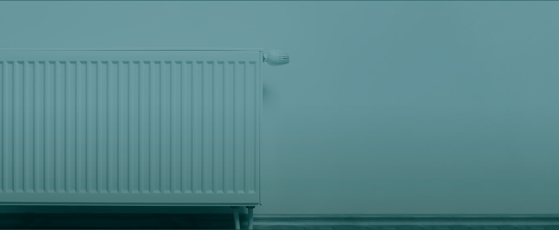 Heizung an einer hellblauen Wand, mit vertikalen Lamellen und einem Thermostat oben rechts.