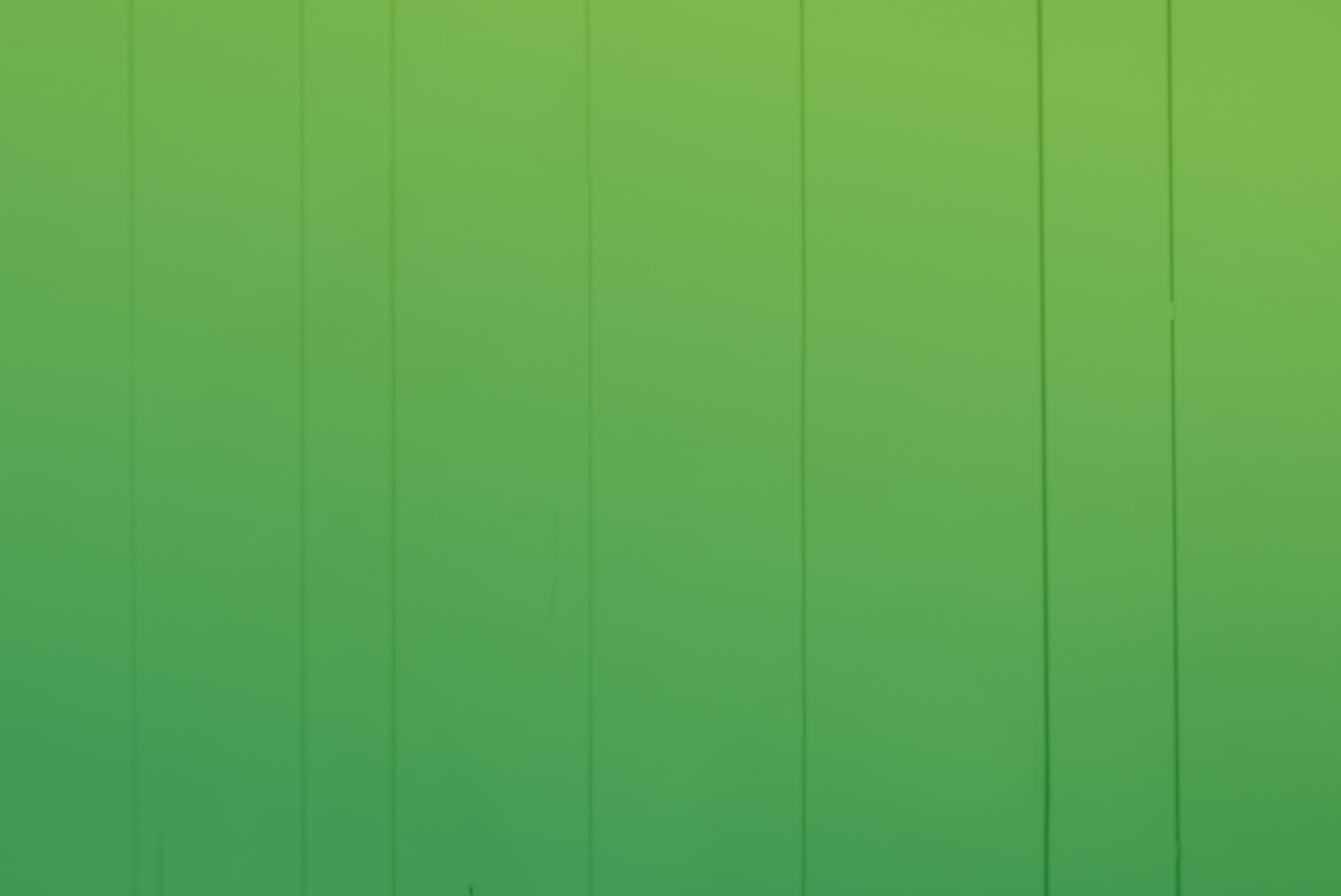 Grüne Wand mit vertikalen Streifen, sanfte Farbverläufe von hellgrün zu dunkelgrün.